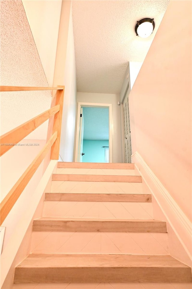 staircase featuring a textured ceiling