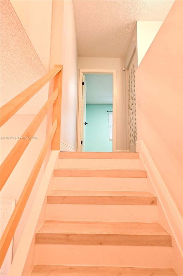 staircase featuring a textured ceiling