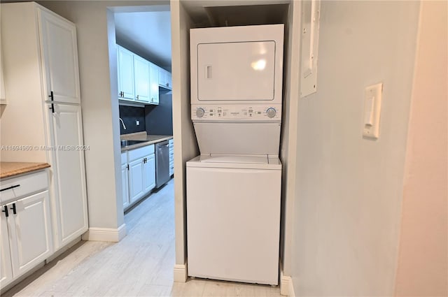 laundry room with stacked washer and dryer, light hardwood / wood-style flooring, and sink