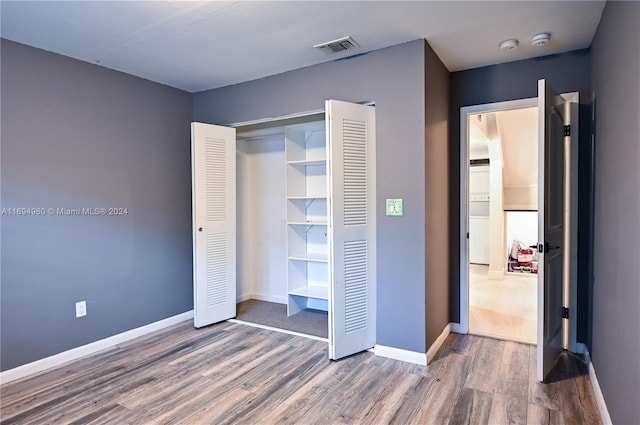 unfurnished bedroom with hardwood / wood-style floors and a closet