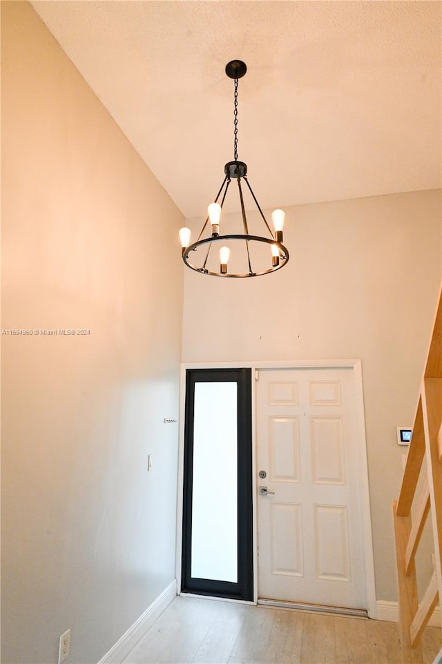 foyer with light hardwood / wood-style floors, lofted ceiling, and an inviting chandelier