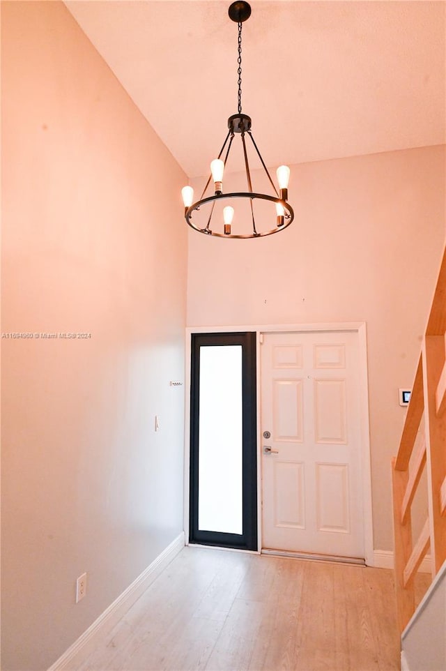 entryway with high vaulted ceiling, light hardwood / wood-style floors, and a notable chandelier