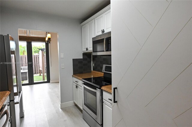 kitchen featuring white cabinets, light wood-type flooring, stainless steel appliances, and tasteful backsplash