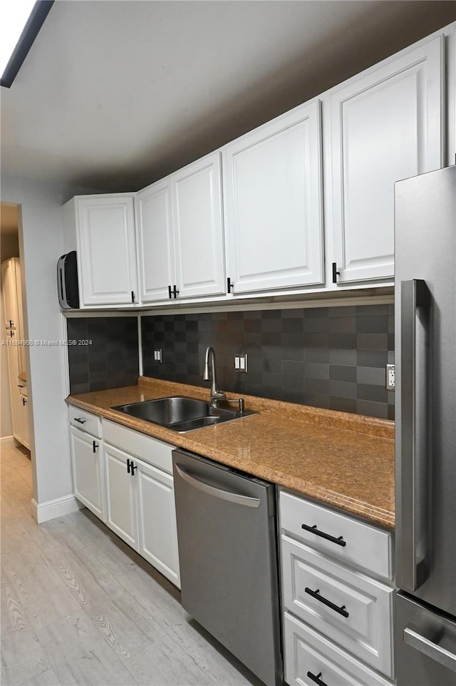 kitchen with white cabinetry, sink, stainless steel appliances, decorative backsplash, and light wood-type flooring