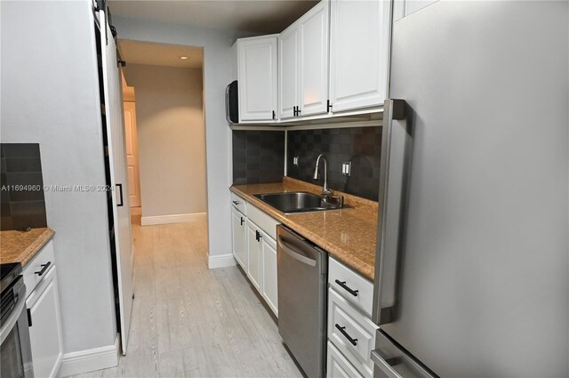 kitchen with appliances with stainless steel finishes, sink, stone countertops, light hardwood / wood-style flooring, and white cabinetry