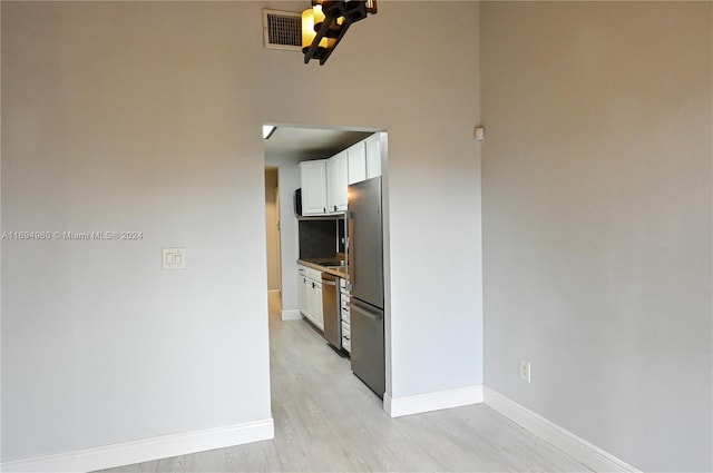 kitchen with light wood-type flooring, white cabinetry, and appliances with stainless steel finishes