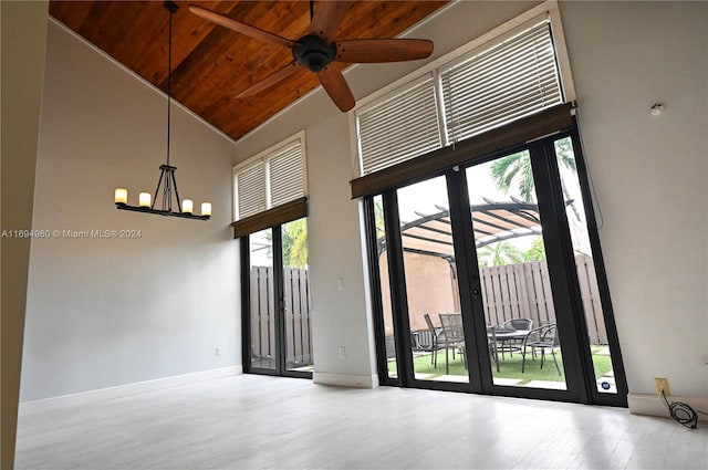 unfurnished room featuring a wealth of natural light, high vaulted ceiling, wooden ceiling, and ceiling fan with notable chandelier