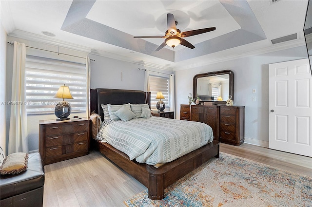 bedroom featuring light hardwood / wood-style flooring, a raised ceiling, ceiling fan, and ornamental molding