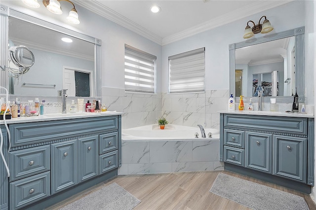 bathroom with tiled tub, hardwood / wood-style flooring, vanity, and ornamental molding