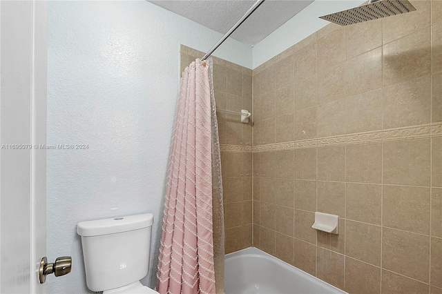 bathroom featuring shower / bathtub combination with curtain, a textured ceiling, and toilet