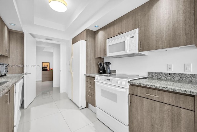 kitchen with light stone countertops, white appliances, and light tile patterned flooring