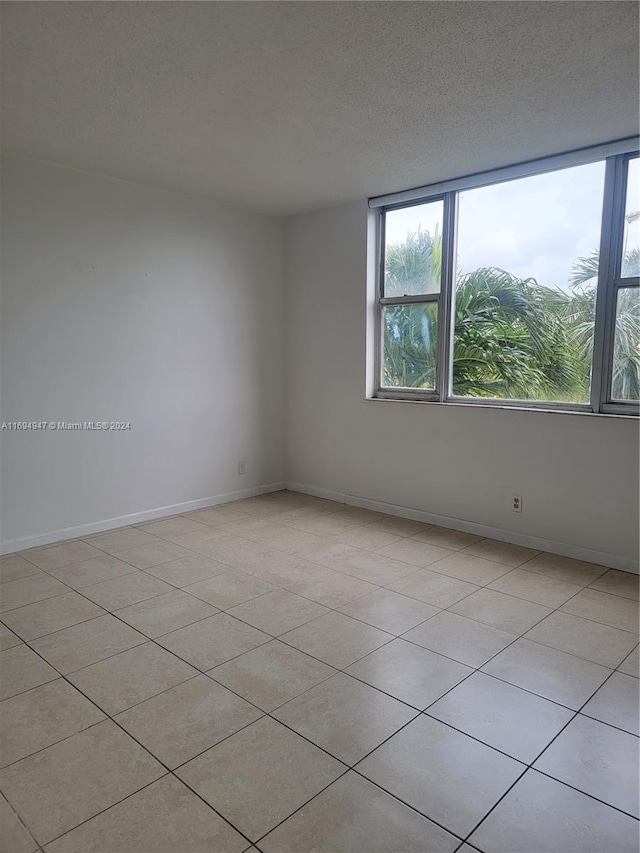 tiled empty room featuring a textured ceiling