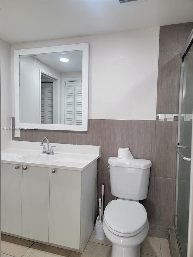 bathroom featuring tile patterned flooring, vanity, tile walls, and toilet