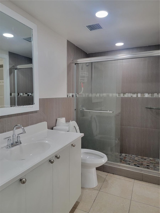 bathroom with tile patterned floors, vanity, an enclosed shower, and toilet