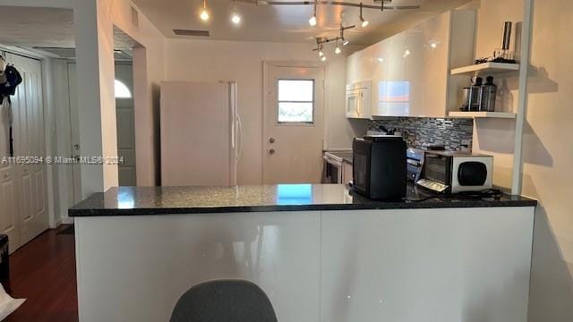 kitchen with white appliances, rail lighting, tasteful backsplash, dark hardwood / wood-style flooring, and white cabinetry