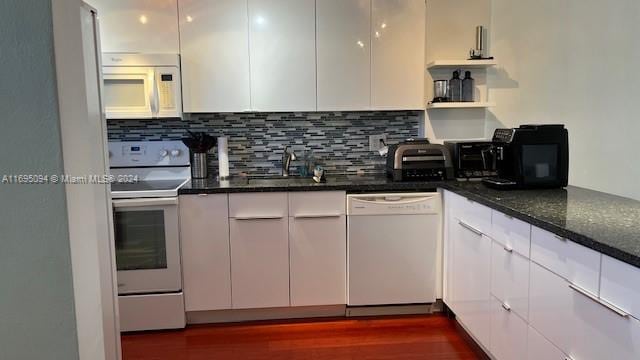 kitchen featuring white appliances, sink, dark stone countertops, white cabinets, and dark hardwood / wood-style floors