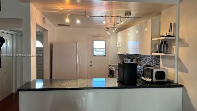 kitchen with white cabinets, white appliances, backsplash, and track lighting