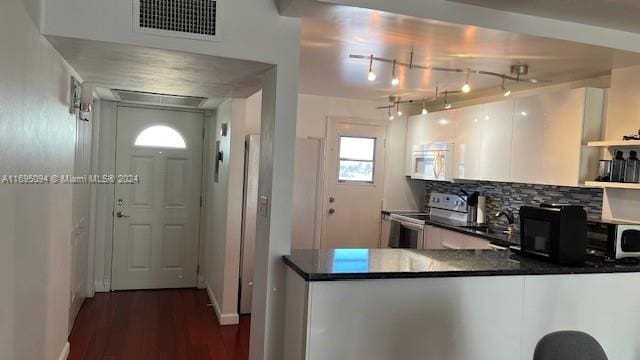 kitchen with kitchen peninsula, dark hardwood / wood-style floors, decorative backsplash, stainless steel electric range oven, and white cabinetry