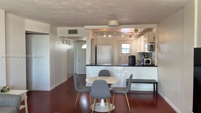 dining area with dark hardwood / wood-style flooring and a textured ceiling