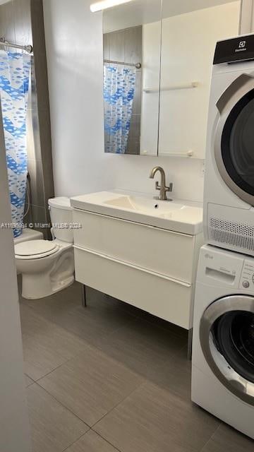 interior space with dark tile patterned floors, stacked washing maching and dryer, and sink