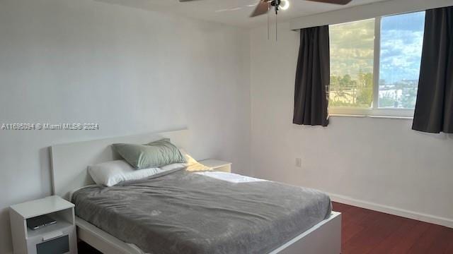 bedroom featuring ceiling fan, dark hardwood / wood-style floors, and multiple windows