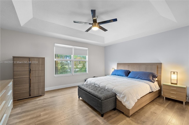 bedroom featuring hardwood / wood-style floors, ceiling fan, and a tray ceiling