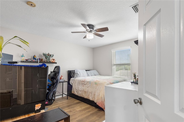 bedroom featuring ceiling fan, light wood-type flooring, and a textured ceiling