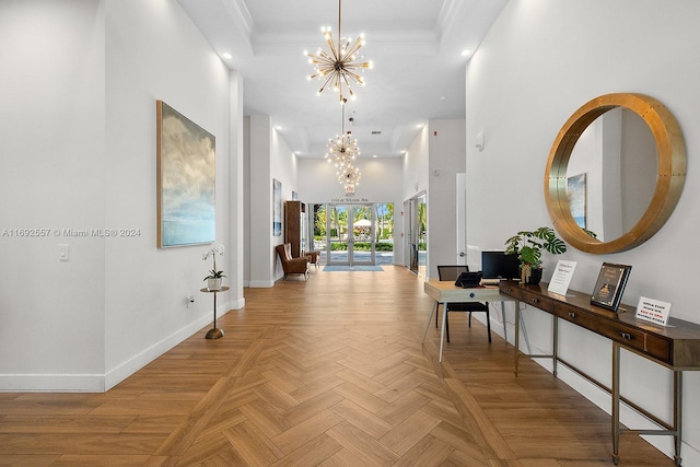 hall featuring light parquet flooring, a towering ceiling, ornamental molding, and a notable chandelier