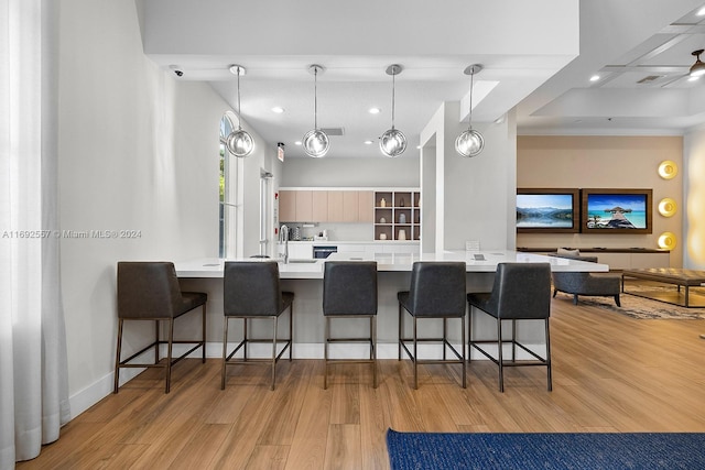 kitchen featuring a breakfast bar, light brown cabinets, decorative light fixtures, and light hardwood / wood-style flooring