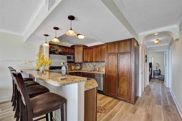 kitchen with a peninsula, stainless steel appliances, backsplash, light stone countertops, and a kitchen bar