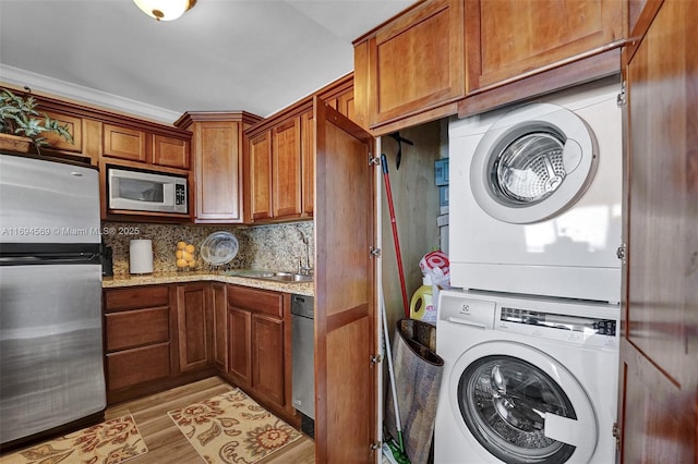 laundry room with stacked washer and dryer, laundry area, a sink, and light wood-style flooring