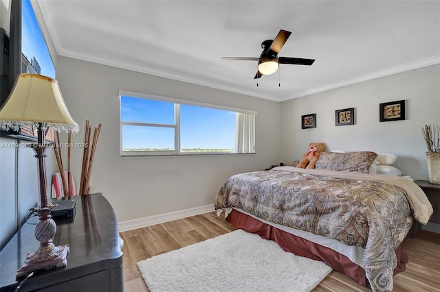 bedroom with ceiling fan, crown molding, baseboards, and wood finished floors