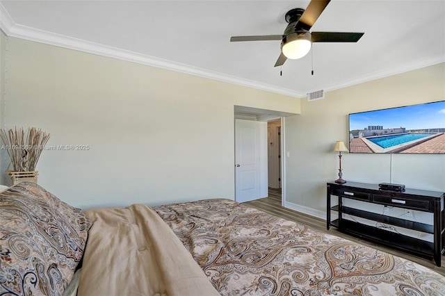 bedroom with ceiling fan, visible vents, crown molding, and wood finished floors