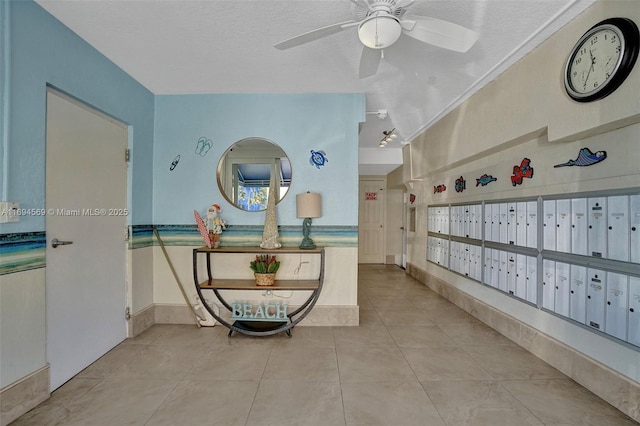 hall featuring a textured ceiling, mail area, and tile patterned floors