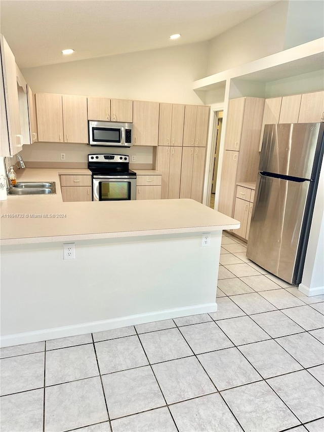 kitchen featuring sink, vaulted ceiling, light brown cabinetry, appliances with stainless steel finishes, and kitchen peninsula