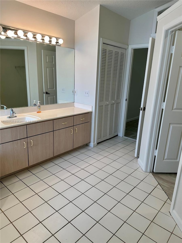 bathroom with tile patterned floors, vanity, and a textured ceiling