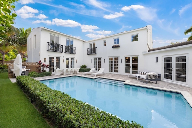 rear view of property with a patio area, a balcony, and french doors