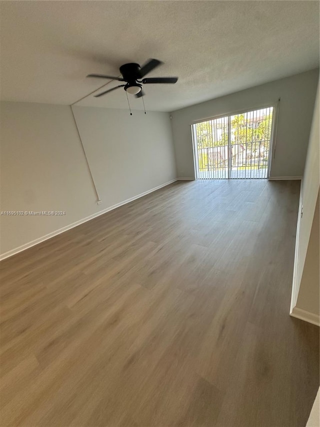 empty room featuring ceiling fan, wood-type flooring, and a textured ceiling