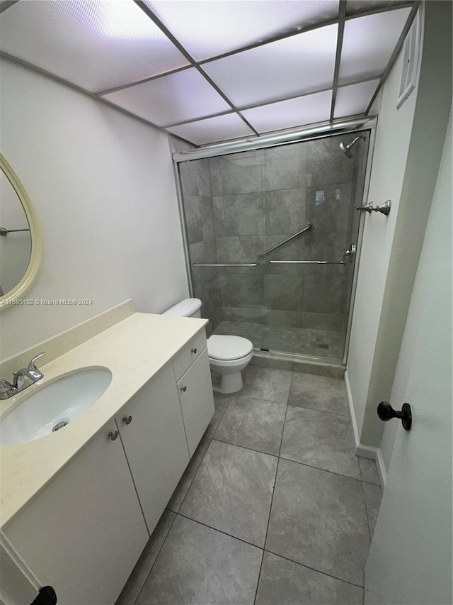 bathroom with tile patterned flooring, vanity, an enclosed shower, and toilet