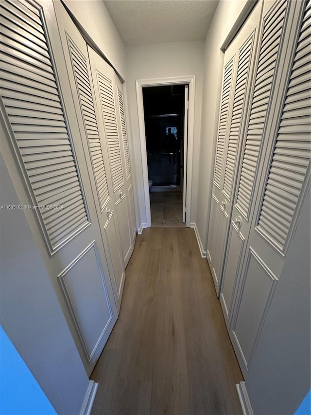 corridor featuring dark hardwood / wood-style flooring and a textured ceiling