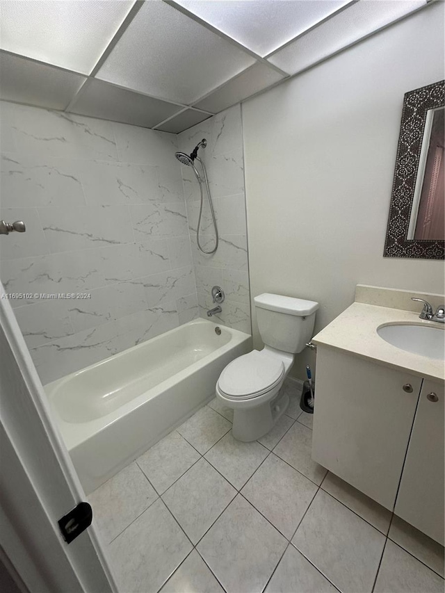 full bathroom featuring a paneled ceiling, tile patterned floors, vanity, tiled shower / bath combo, and toilet