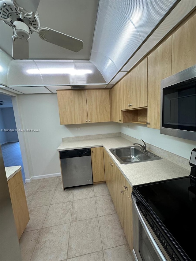 kitchen with light brown cabinets, sink, light tile patterned floors, and stainless steel appliances