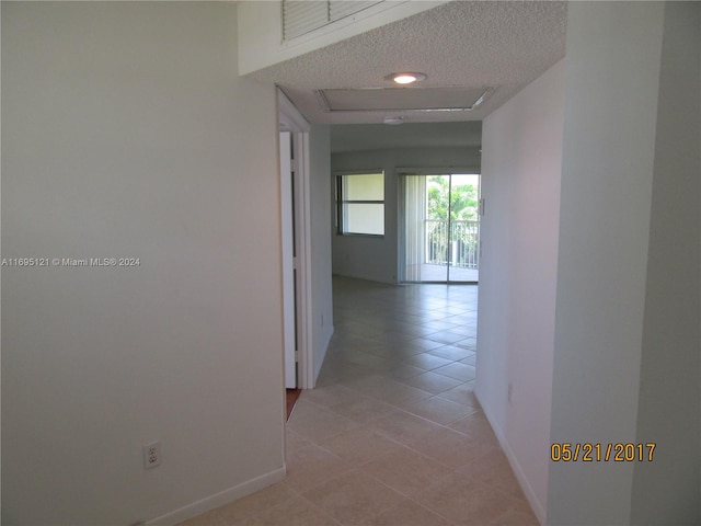 hallway with light tile patterned flooring and a textured ceiling