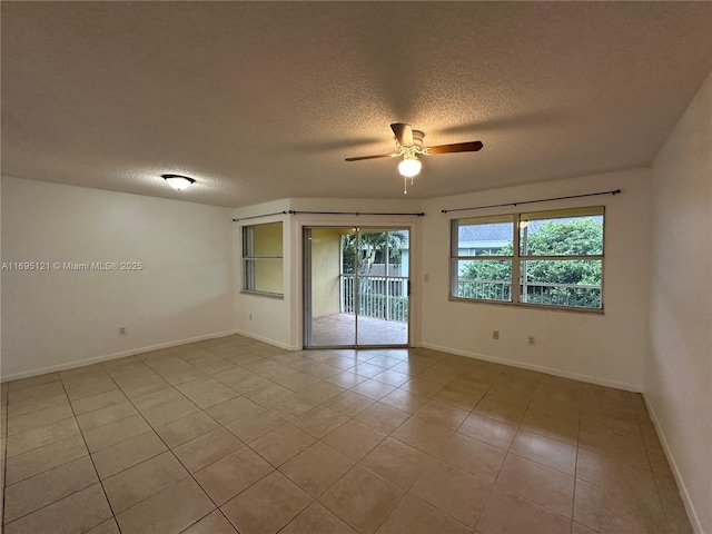 empty room with light tile patterned floors, baseboards, a textured ceiling, and ceiling fan