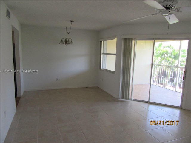 tiled empty room featuring ceiling fan with notable chandelier