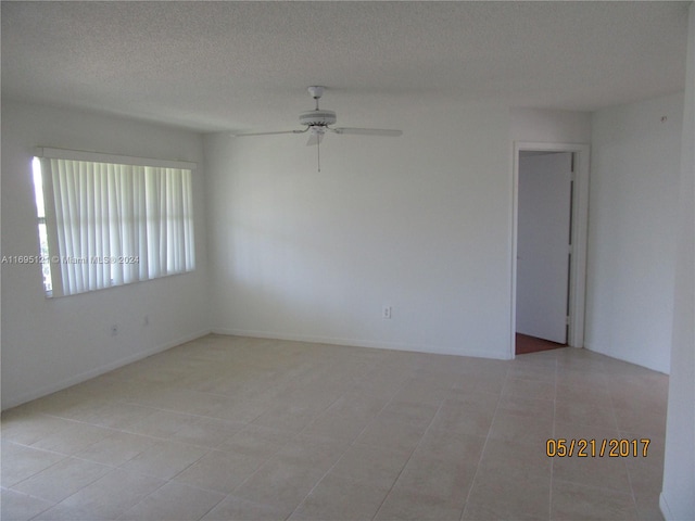 spare room with ceiling fan, light tile patterned floors, and a textured ceiling