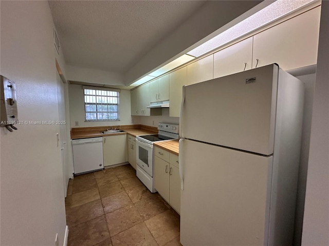 kitchen featuring under cabinet range hood, visible vents, white appliances, and butcher block counters