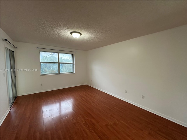 empty room with dark wood-type flooring, baseboards, and a textured ceiling