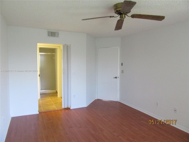 spare room with hardwood / wood-style floors, ceiling fan, and a textured ceiling