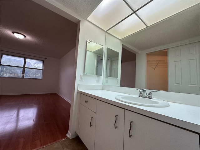 bathroom with vanity, vaulted ceiling, wood finished floors, and a textured ceiling